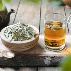Napar z liści senesu w szklance, obok miseczka z suszem i drewniana łyżka. To naturalny sposób na zdrowie.