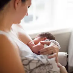 Matka karmi piersią dziecko, zastanawiając się, czy ibuprofen jest bezpieczny podczas karmienia.