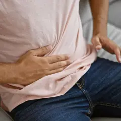 Mężczyzna trzyma się za brzuch, odczuwając ból jelit. Przyczyny mogą być różne, od niestrawności po poważniejsze schorzenia.