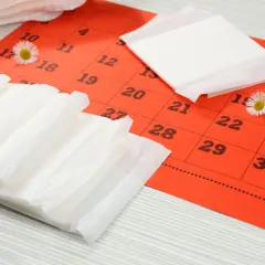 Kalendarz z zaznaczonymi dniami i podpaskami. Czy zastanawiasz się, jak przyspieszyć okres?