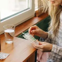 Kobieta przygotowuje tabletki z suplementem. Zastanawia się, kiedy brać cynk rano czy wieczorem, by uzyskać najlepsze efekty.