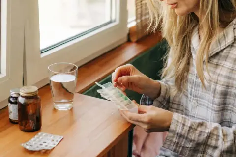 Kobieta przygotowuje tabletki z suplementem. Zastanawia się, kiedy brać cynk rano czy wieczorem, by uzyskać najlepsze efekty.