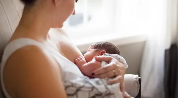 Matka karmi piersią dziecko, zastanawiając się, czy ibuprofen jest bezpieczny podczas karmienia.