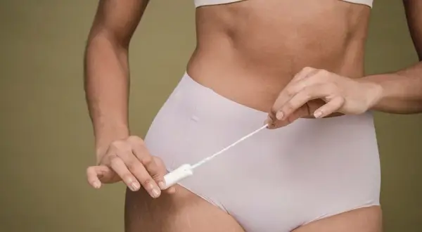 Kobieta trzymająca tampon. Długotrwały brak miesiączki skutki mogą być niepokojące, warto skonsultować się z lekarzem.